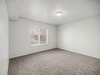 Empty carpeted bedroom with window and blinds at Brentwood Park Apartments, La Vista, NE