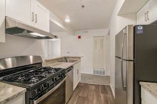 Galley kitchen with gas stove and stainless refrigerator at Brentwood Park Apartments, Nebraska, 68128