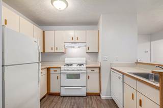 Galley kitchen with white appliances and wood trim at Brentwood Park Apartments, La Vista, NE 68128