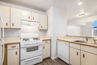 Compact kitchen with white appliances and wood trim at Brentwood Park Apartments, La Vista, NE