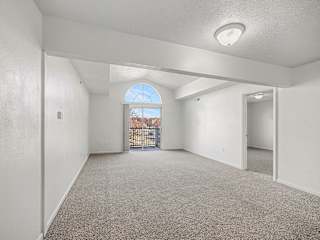 Empty living room with arched window and balcony door at Brentwood Park Apartments, Nebraska, 68128