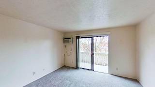 A living room with a sliding glass door leading to a balcony at Briarwood Apartments in Benton Harbor, MI