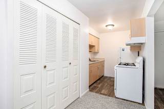 Galley kitchen with louvered closet doors and gas range at Brookside Apartments, Springfield, MI 49037