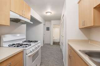 Galley kitchen with gas range and wood cabinets at Brookside Apartments, Springfield, MI