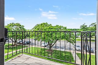 Balcony view overlooking parking lot and mature trees at Brookside Apartments, Springfield
