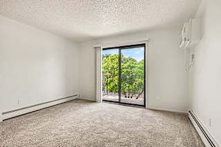 Empty carpeted room with balcony access and greenery views at Brookside Apartments, Springfield
