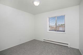 Empty carpeted bedroom with window and blinds at Brookside Apartments, Springfield, MI