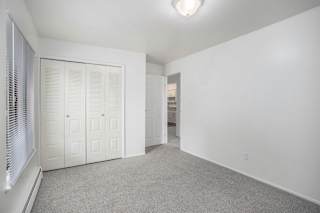Empty carpeted bedroom with bifold closet doors at Brookside Apartments, Springfield, 49037