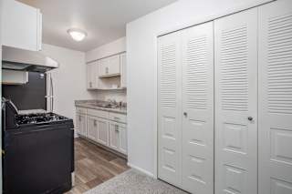 Kitchen with louvered closet doors and gas stove at Brookside Apartments, Michigan, 49037