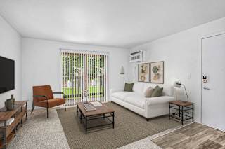 Living room with white couch and brown armchair at Brookside Apartments, Springfield, MI 49037