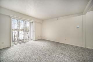 an empty living room with a sliding glass door to a balcony at Canal 2 Apartments in Lansing, MI