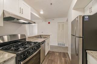 a kitchen with stainless steel appliances and white cabinets at Canal 2 Apartments in Lansing, MI