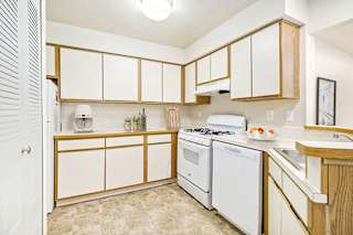 A kitchen with white appliances and wooden cabinets at Canal Club Apartments, Lansing, 48917