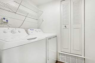 A white laundry room with a washing machine and dryer at Canal Club Apartments in Lansing, MI