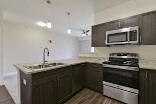 A kitchen with stainless steel appliances and a breakfast bar at Chase Creek Apartment Homes, Alabama, 35811