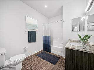 Bathroom with tub shower combo and wood style flooring at Chase Creek Apartments Homes, Huntsville, Alabama