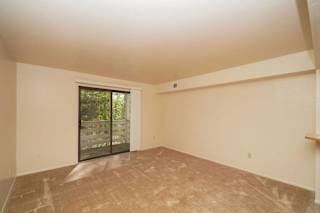 A living room with a slider to a balcony at Canal Club Apartments, Lansing, 48917