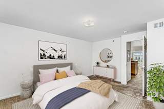 Modern bedroom with grey headboard and white dresser at Colonial Pointe at Fairview Apartments, Bellevue, NE