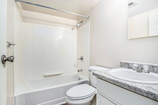 A white, upgraded bathroom with a toilet, sink, and bathtub at Concord Place Apartments, Kalamazoo, MI
