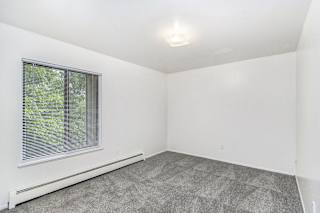 A spacious bedroom with a window and carpeted floor at Concord Place Apartments, Kalamazoo, MI