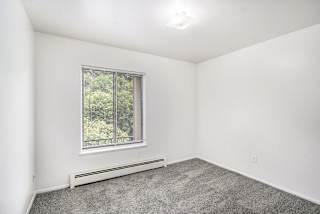 A bedroom with a window and plush carpeting at Concord Place Apartments, Kalamazoo, MI