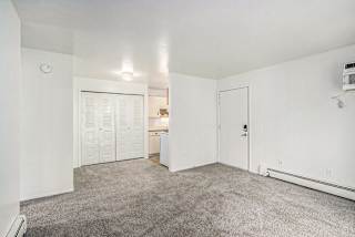 A large empty living/dining room with a carpeted floor and a large closet at Concord Place Apartments, Kalamazoo, MI