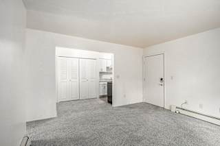 A living and dining room with a carpeted floor leading to a kitchen at Concord Place Apartments, Kalamazoo, MI