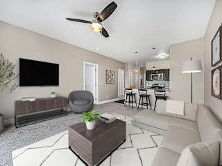 A living room with a grey armchair, a white sofa, a wooden coffee table at Copper Creek Apartment Homes, Maize, Kansas