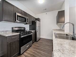 A kitchen with dark wood cabinets and stainless steel appliances at Copper Creek Apartment Homes, Maize