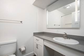 A renovated bathroom with a large vanity area and mirror at The Crossings Apartments, Grand Rapids