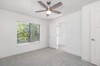 A bedroom with a ceiling fan and a window with blinds at The Crossings Apartments, Grand Rapids, 49508