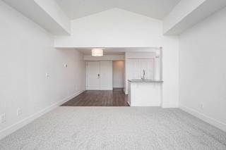 A large, empty living and dining room with a carpeted floor at The Crossings Apartments, Grand Rapids