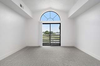 A living room with a cathedral ceiling and large arched window and a view at The Crossings Apartments, Grand Rapids