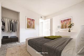 a bedroom with white walls and a large bed with a green blanket at Timberbrook Apartments, Peoria, IL, 61614