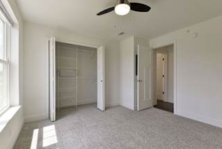 A bedroom with a large closet with wardrobe organizers at Dodson Pointe Apartment Homes, Rogers