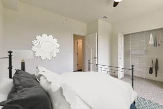A spacious bedroom with a bed and a closet with organizers at Dodson Pointe Apartment Homes, Rogers, AR