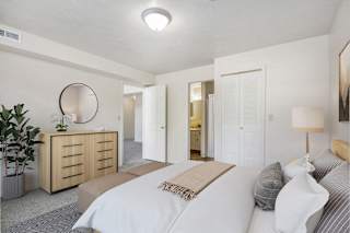 A master bedroom with a large bed , walk-in closet and ensuite bathroom with a shower at Dupont Lakes Apartments in Fort Wayne, IN