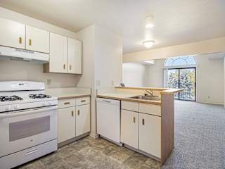 A kitchen with white appliances and a breakfast bar at Dupont Lakes Apartments in Fort Wayne, IN