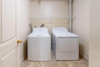 A full-size washer and dryer in a small laundry room at Dupont Lakes Apartments in Fort Wayne, IN