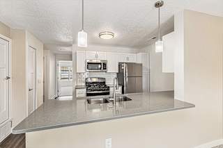Living room with carpet leading to kitchen at Eagle Ridge Apartment Homes,  Michigan 49685