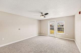 A living room with a ceiling fan and a french door to the outside at Eagle Ridge Apartment Homes, Traverse City, MI 49685