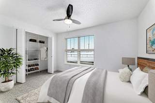 A bedroom with a large bed, a walk in closet and ceiling fan at Eagle Ridge Apartment Homes, Traverse City, MI 49685