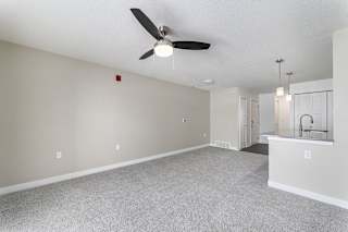 A living room with a ceiling fan and a carpeted floor at Eagle Ridge Apartment Homes, Traverse City, Michigan