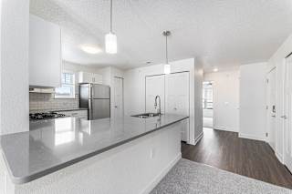 A modern kitchen with white cabinets and a grey countertop at Eagle Ridge Apartment Homes, Traverse City
