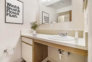 Bathroom vanity with white countertop and wooden cabinets at Emerald Park Apartments, Michigan, 49001