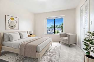 Furnished bedroom with neutral tones and upholstered chair at Emerald Park Apartments, Kalamazoo, MI 49001