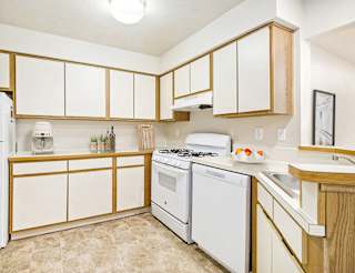 Kitchen with white appliances and oak trim at Emerald Park Apartments, Kalamazoo, MI