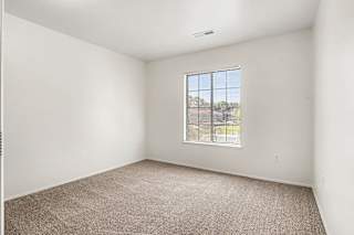 A bedroom with a carpeted floor and a window with a view at Emerald Park Apartments, Kalamazoo, Michigan