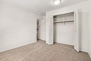 A white closet with a carpeted floor and a white door at Emerald Park Apartments, Kalamazoo, Michigan