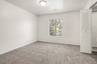 A bedroom with a window and a door to a walk-in closet at Emerald Park Apartments, Kalamazoo, Michigan